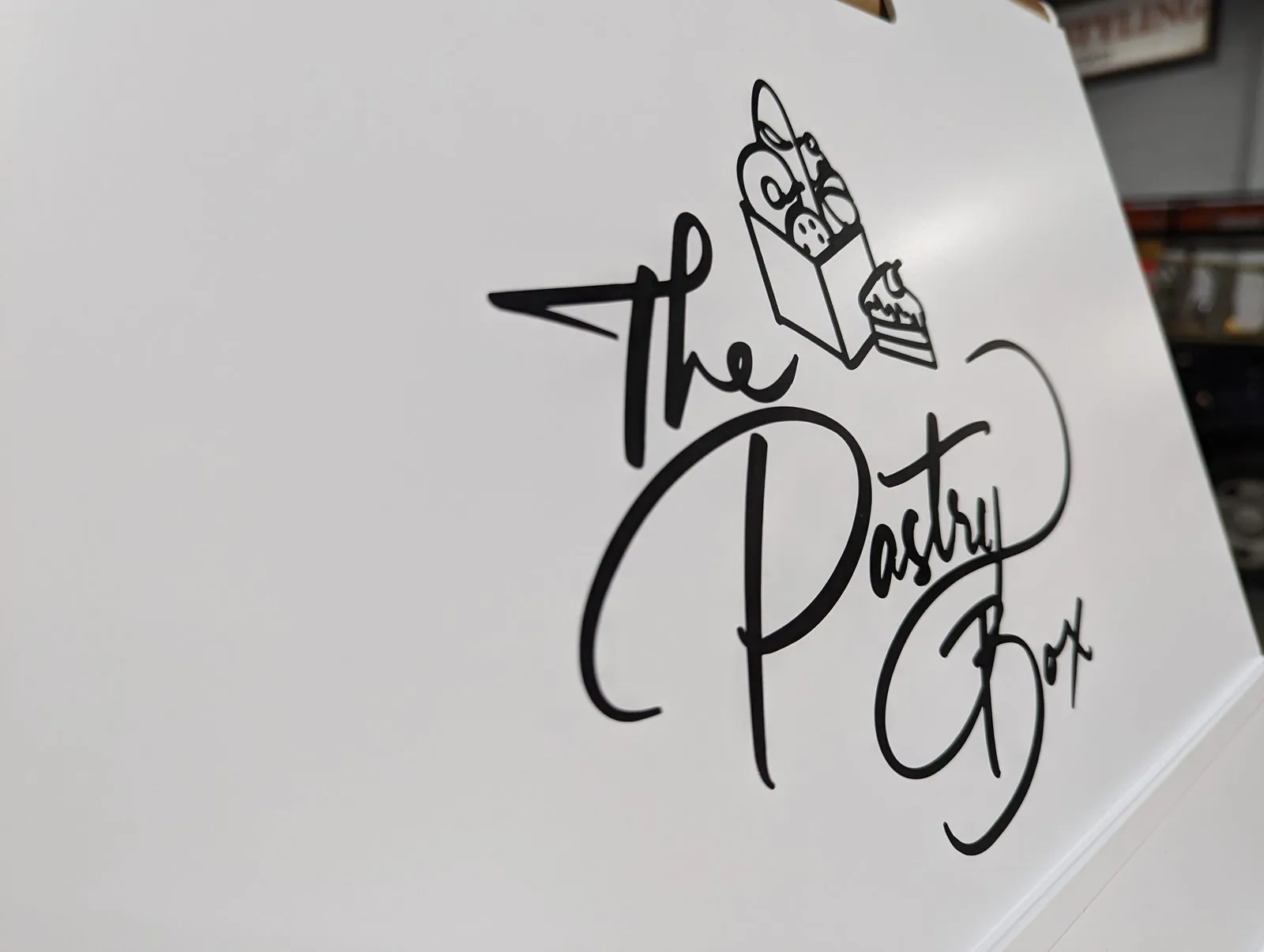 Black script logo on a white sidewalk sign face