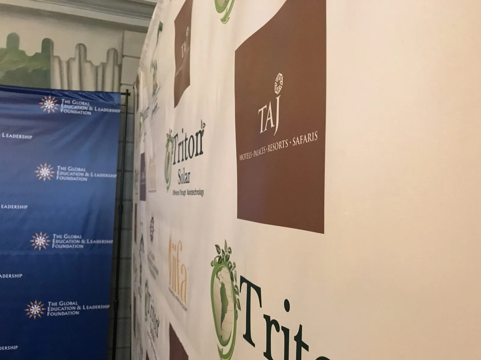 Angled close up of a white sponsor wall with brown and green logos beside a navy backdrop
