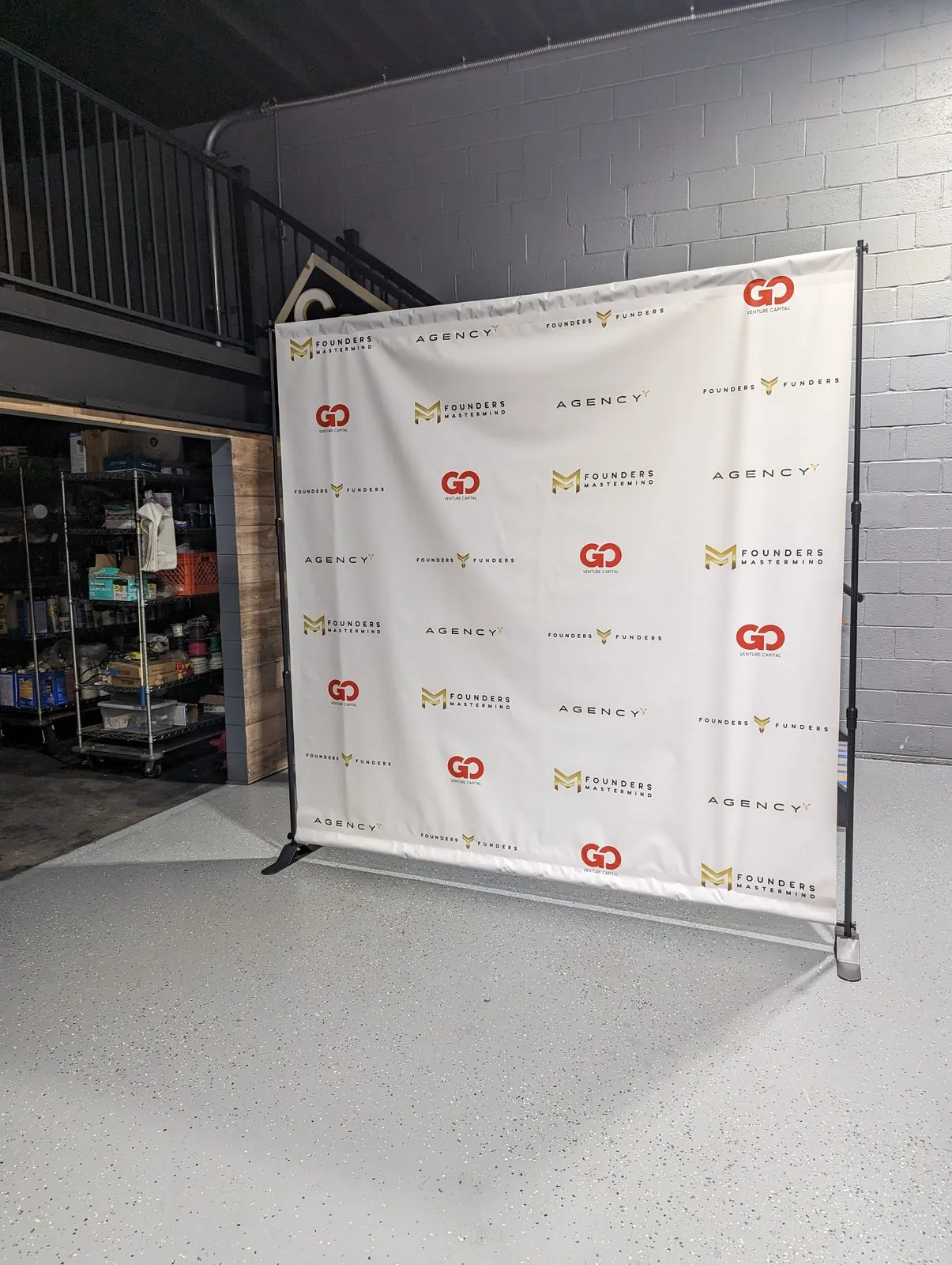 White step and repeat backdrop with red and gold logos hung on a frame in our shop