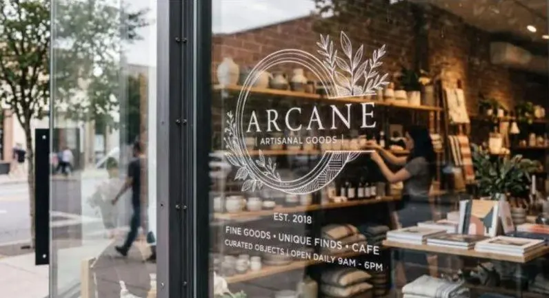 White window decal with a shop logo, store hours and services on a glass storefront