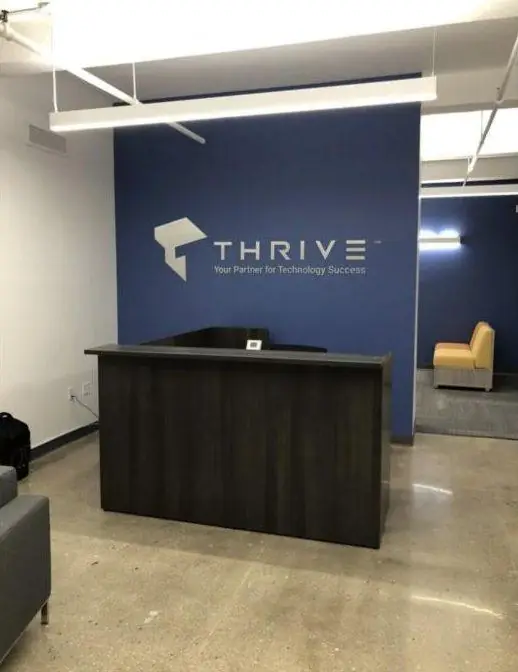 Thrive logo in white dimensional letters on a blue lobby wall behind a reception desk in New Jersey