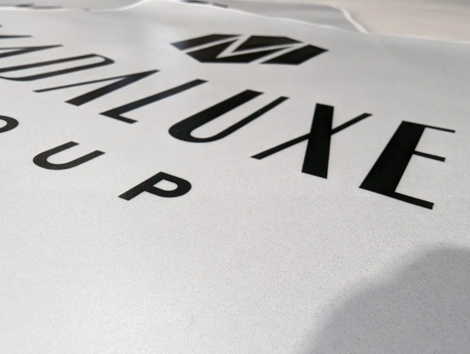 Close up of black cut vinyl letters on a white liner with the waste vinyl weeded away