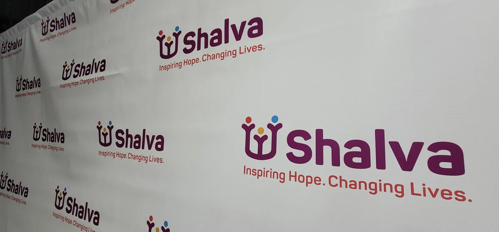Angled view of a white step and repeat backdrop with purple and red logos
