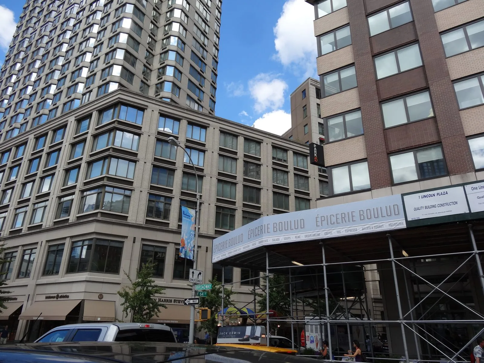 White sidewalk shed banner wrapping the corner of a tall brick building