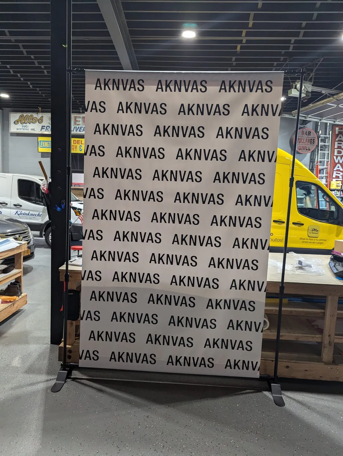 White step and repeat backdrop with a black name pattern on a frame in our shop
