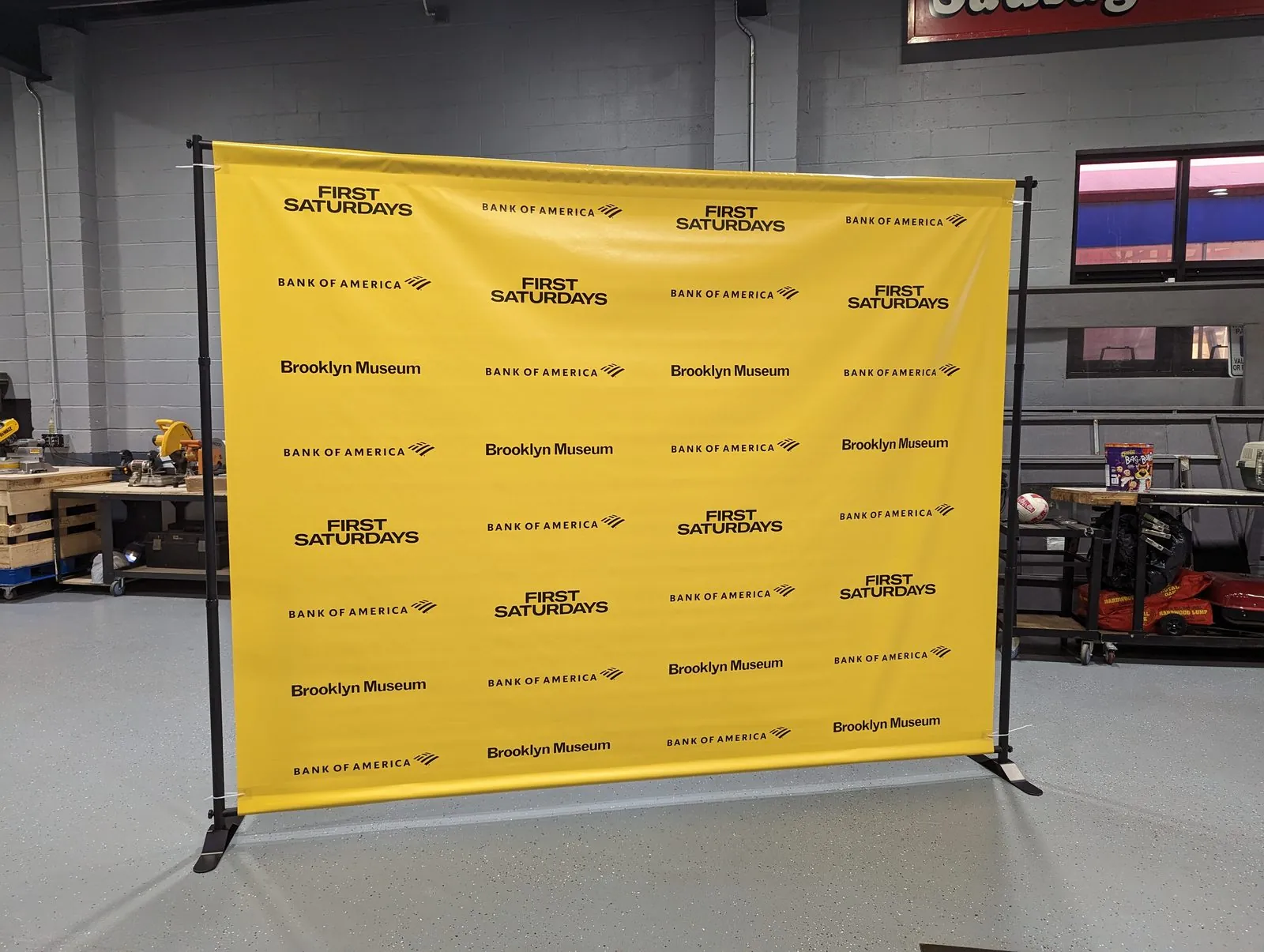 Yellow step and repeat backdrop with rows of black logos on a frame in our shop